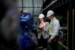 bedrijf vrouw en Mens vergadering en controle nieuw machine robot. ingenieur wandelen Bij magazijn industrie machine. bedrijf onderhandeling concepten en technologie. vrouw is gebruik makend van slim tablet naar Cadeau Mens. foto