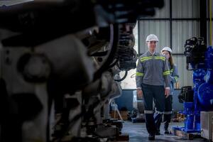 fabriek ingenieur vrouw inspecteren Aan machine met slim tablet. arbeider werken Bij machine robot arm. de lassen machine met een afgelegen systeem in een industrieel fabriek. kunstmatig intelligentie- concept. foto