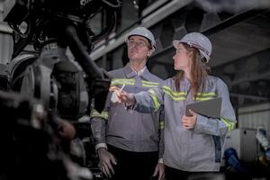 verkoop manager en fabriek eigenaar in pakken onderhandelen verkoop robots gebruikt in de fabriek. bedrijf ingenieurs vergadering en controle nieuw machine robot. arbeiders wandelen Bij magazijn lassen machine. foto