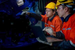 fabriek ingenieurs inspecteren Aan machine met slim tablet. arbeider werken Bij zwaar machine robot arm. de lassen machine met een afgelegen systeem in een industrieel fabriek. kunstmatig intelligentie- concept. foto