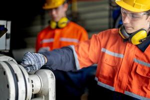 ingenieur Mens controle de toestand van machine en gebruikt moersleutel naar schroef sommige een deel van uitrusting Bij cnc fabriek. arbeider vervelend veiligheid bril en helm. onderhoud en repareren concept. foto