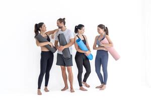 groep van gelukkig sportief meisjes en vent vervelend lichaam elegant sportkleding Holding persoonlijk tapijten leunde Aan een wit achtergrond. aan het wachten voor yoga klasse of lichaam gewicht klas. gezond levensstijl en welzijn foto