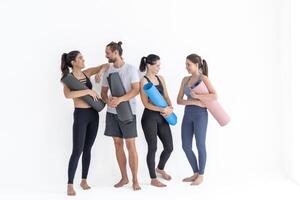 groep van gelukkig sportief meisjes en vent vervelend lichaam elegant sportkleding Holding persoonlijk tapijten leunde Aan een wit achtergrond. aan het wachten voor yoga klasse of lichaam gewicht klas. gezond levensstijl en welzijn foto