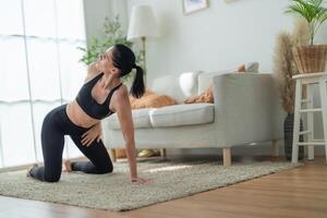 dichtbij omhoog Dames zelfverzekerd opleiding yoga. atletisch Dames in sportkleding aan het doen geschiktheid uitrekken opdrachten Bij huis in de leven kamer. sport en recreatie concept. yoga leraar is helpen meisje. foto