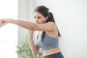 aantrekkelijk en sterk vrouw uitrekken voordat geschiktheid Bij binnen- huis. gezond levensstijl. vrouw warm omhoog door boksen in de lucht. jong vrouw met slank lichaam ponsen boksen voetenwerk cardio oefening. foto