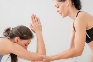 twee Dames zelfverzekerd opleiding yoga. atletisch Dames in sportkleding aan het doen geschiktheid uitrekken opdrachten Bij huis in de leven kamer. sport en recreatie concept. yoga leraar is helpen jong vrouw. foto