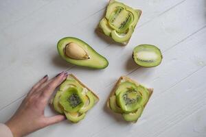 de boterhammen met avocado en kiwi Aan een wit houten achtergrond. foto