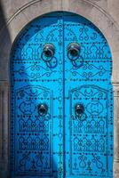 een blauw deur met zwart hengsten en steen ornament Bij deuropening in Tunesië foto