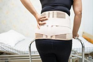 aziatische damepatiënt met rugpijnsteunriem voor orthopedische lumbale met rollator. foto