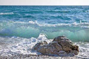 Golf uit de kust in de buurt een groot steen. zomer zee. turkoois water foto