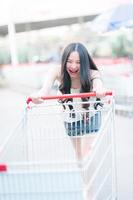 Aziatisch vrouw voortvarend boodschappen doen kar in boodschappen doen winkelcentrum foto