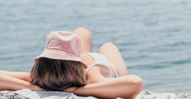 onherkenbaar positief vrouw in wit bikini zonnen of bruinen Aan kust strand gedurende zomer. gelukkig toerist genieten van zon bruinen aan het liegen Aan strand stoel lounge Bij luxe toevlucht foto