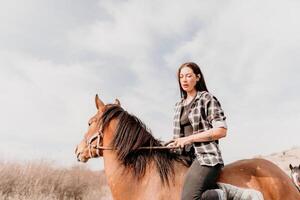 jong gelukkig vrouw in hoed met haar paard in avond zonsondergang licht. buitenshuis fotografie met mode model- meisje. levensstijl humeur. concept van buitenshuis rijden, sport- en recreatie. foto