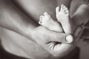 vader Holding pasgeboren baby voeten Aan zijn handen foto