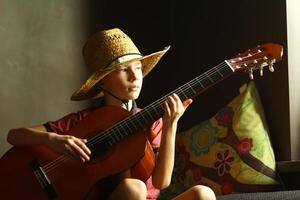 portret van een Kaukasisch jongen vervelend een rietje hoed en spelen de gitaar foto