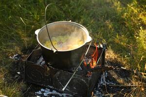 ketel met een hanger Aan een Open brand buitenshuis. picknick camping concept foto