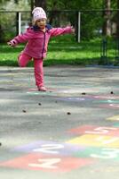 drie jaar oud meisje jumping en spelen hinkelen in de park foto