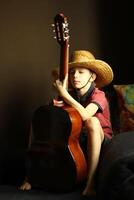 portret van een Kaukasisch jongen vervelend een rietje hoed en spelen de gitaar foto