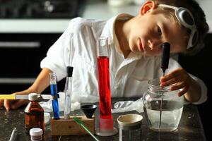 jong wetenschapper chemicus grijnzend terwijl maken zijn wetenschappelijk experimenten. kinderen in stam foto