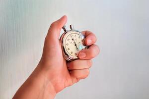 hand- Holding een stopwatch en drukken de knop naar Notitie de tijd. foto