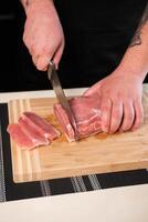 stukken van vlees zijn besnoeiing met een mes Aan een bord foto