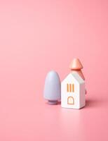 huis en bomen in mooi kleuren. kopen een huis. mooi zo huisvesting. hypotheek. knus en teder tonen. pastel roze kleuren. foto