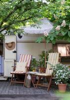 terras mobiel huis in lente, mobiel huis, groen bladeren, zon ligstoel met deken, bloempot, tafel en vreugdevuur foto