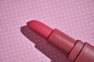 roze lippenstift Aan een Purper polka punt achtergrond. foto