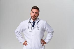 jong knap modern dokter in een wit medisch japon staat in de studio Aan een wit achtergrond. leerling stagiair van een medisch Universiteit. foto