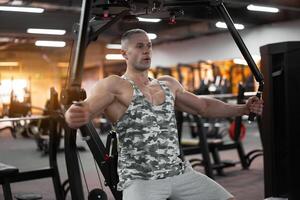 gespierd atletisch bodybuilder zittend bank opleiding borst spieren Aan geschiktheid uitrusting foto