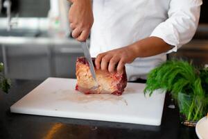 onherkenbaar jong Afrikaanse chef staand in professioneel keuken in restaurant voorbereidingen treffen een maaltijd van vlees en kaas groenten. foto