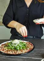 gastvrouw maken carpaccio Aan marmeren keuken aanrecht met haar handen foto