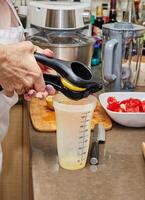 professioneel chef knijpen vers citroen sap in meten kop in modern keuken foto