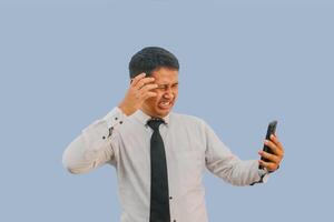 volwassen Aziatisch Mens geschokt gezicht terwijl op zoek naar mobiel telefoon foto