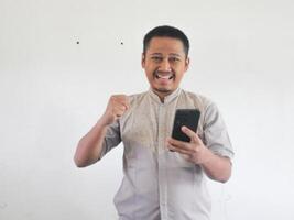 Aziatisch Mens Holding zijn mobiel telefoon met echt uitdrukking foto