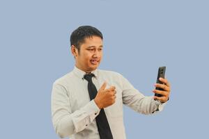 volwassen Mens Aziatisch met vlak uitdrukking en geven duim naar mobiel telefoon foto