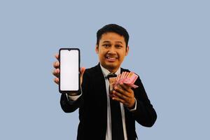volwassen Aziatisch Mens glimlachen gelukkig terwijl tonen blanco mobiel telefoon scherm en Holding papier geld foto