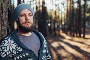 een jong Mens met een baard wandelingen in een pijnboom Woud. portret van een brutaal gebaard Mens herfst Woud foto