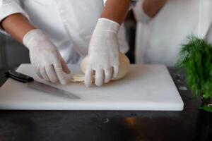 onherkenbaar jong Afrikaanse chef staand in professioneel keuken in restaurant voorbereidingen treffen een maaltijd kaas. foto