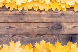 herfst bladeren kader Aan houten achtergrond top visie vallen grens geel en oranje bladeren wijnoogst hout tafel kopiëren ruimte voor tekst. foto