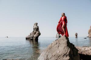 vrouw reizen zee. jong gelukkig vrouw in een lang rood jurk poseren Aan een strand in de buurt de zee Aan achtergrond van vulkanisch rotsen, Leuk vinden in IJsland, sharing reizen avontuur reis foto