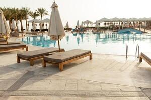 zwemmen zwembad met sjees lounge en zonnescherm Bij tropisch toevlucht foto