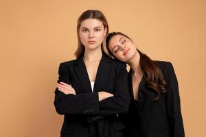twee jong bedrijf vrouw gekleed zwart pak staand studio oranje kleur achtergrond foto