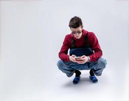 jong knap vent in zonnebril en rood capuchon met een borst tuigage zak poseren in de studio Aan een wit achtergrond foto