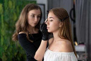 jong schoonheidsspecialist Kaukasisch meisje houdt model- wenkbrauw correctie foto