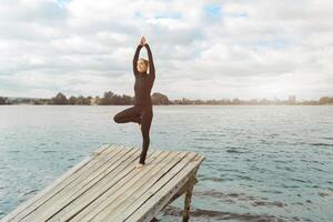 fitheid, sport, mensen en levensstijl concept - jong vrouw maken yoga opdrachten Aan strand foto