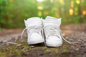 gebruikt wit hoog sportschoenen staan Aan een landelijk weg dat loopt in de Woud. foto