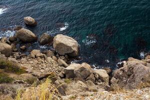 groot steen rots over- de zee water foto