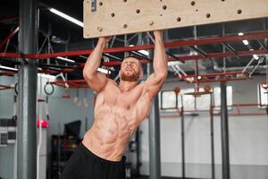 Mens beklimming Pegboard Sportschool atleet opleiding arm sterkte uithoudingsvermogen alpinisme binnen. ideaal lichaam met perfect buikspieren naakt torso foto