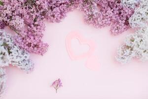 lila takken en twee roze hart Aan een licht roze achtergrond leeg ruimte voor uw tekst, top visie. een groot en een klein hart Leuk vinden simbol van liefde foto